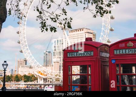 Rote Telefonzellen mit Gebäuden und dem berühmten London Eye im Hintergrund Stockfoto