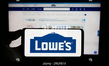 Person, die ein Mobiltelefon mit dem Logo des US-amerikanischen Einzelhandelsunternehmens Lowe's Companies Inc. Auf dem Bildschirm vor der Unternehmenswebseite hält. Konzentrieren Sie sich auf das Display des Telefons. Stockfoto