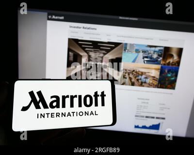 Person, die ein Mobiltelefon mit dem Logo des US-amerikanischen Hotelunternehmens Marriott International Inc. Auf dem Bildschirm vor der Webseite hält. Konzentrieren Sie sich auf das Display des Telefons. Stockfoto