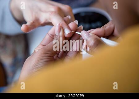 Eine Frau, die sich mit einer Maniküre um ihre Nägel kümmert. Hände einer Person mit Maniküre. Prozessschritte Stockfoto