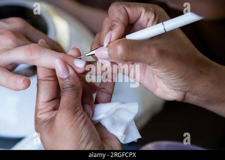 Eine Frau, die sich mit einer Maniküre um ihre Nägel kümmert. Hände einer Person mit Maniküre. Prozessschritte Stockfoto