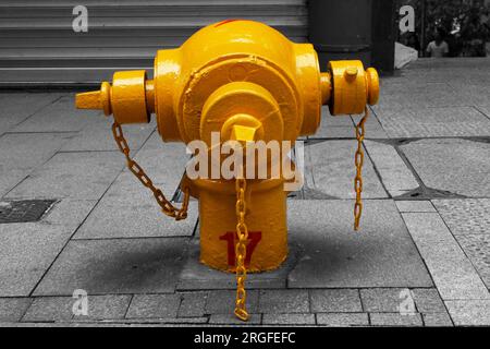 Farbisolierter gelber Hydrant in Hongkong auf schwarz-weißer Umgebung. Stockfoto