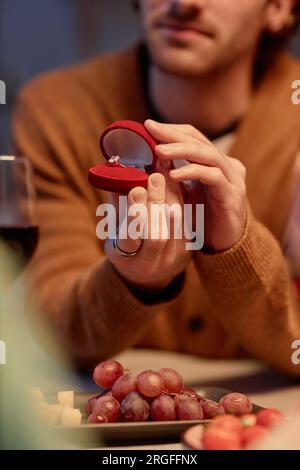 Nahaufnahme eines jungen Mannes, der eine offene Schachtel mit Verlobungsring hielt, während er seiner Freundin beim Abendessen einen Antrag machte Stockfoto