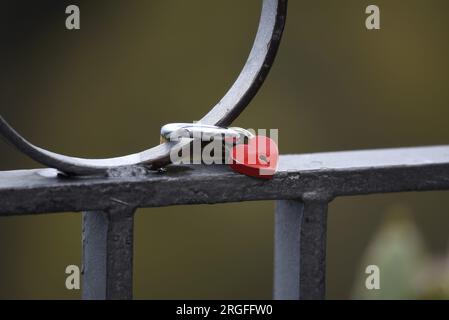 Rotes, herzförmiges Liebesschloss, das auf dem schmiedeeisernen Zaungeländer der Piazza IX Aprile in Taormina, Sizilien, Italien, befestigt ist. Stockfoto