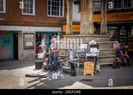 Ein Bluesmusiker in der antiken Stadt Winchester, H, tritt mit einem mechanischen Skeletttrommler vor dem City Cross oder Butter Cross auf Stockfoto