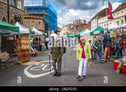 Ein älteres Paar spaziert durch den Wochenend-Antiquitäten- und Kunsthandwerksmarkt in der High Street, Winchester, Hampshire, Großbritannien. Der Markt findet am Samstag und statt Stockfoto