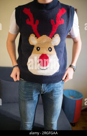 Nicht wiedererkennbarer junger Mann, der eine weihnachtsweste mit Rentieren trägt Stockfoto