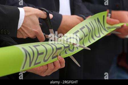 Rostock, Deutschland. 09. Aug. 2023. Für die feierliche Eröffnung des neuen Busbahnhofs am Hauptbahnhof wird ein Band mit der Aufschrift „New Opening“ ausgeschnitten. In einer einjährigen Bauzeit wurde der Busbahnhof der Regionalbus Rostock GmbH (Rebus) grundlegend renoviert, erweitert und barrierefrei gemacht. Von der Kreuzung auf der Südseite des Hauptbahnhofs von Rostock aus verkehren zahlreiche Buslinien in die Umgebung von Rostock. Die Baukosten beliefen sich auf rund drei Millionen Euro. Kredit: Bernd Wüstneck/dpa/Alamy Live News Stockfoto