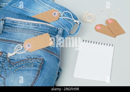 Ein Stapel blauer Jeans und leerer Anhänger auf weißem Hintergrund Stockfoto