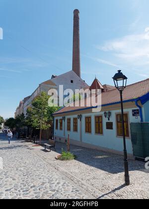 Die berühmte Bohemian Kopfsteinpflaster Straße Skadarlija mit Cafés und Restaurants und Kamin der alten Brauerei. Belgrad, Serbien. August 2023. Stockfoto