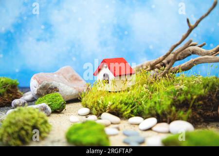 Kleines Holzhaus mit Moos, Treibholz und Steinen. Natürlicher Hintergrund, Kopierraum. Stockfoto
