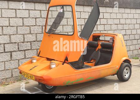 Oldtimer-Orange Bond Bug, kleines britisches dreirädriges Auto mit zwei Sitzen auf der Automesse in Lelystad, Niederlande - Juni 18 2023 Stockfoto