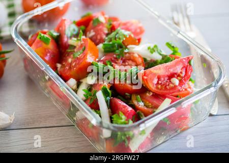 Würzige Snacktomaten mit Knoblauch, Kräutern, Gewürzen und Zwiebeln in einer Glasschüssel auf einem Holztisch. Stockfoto