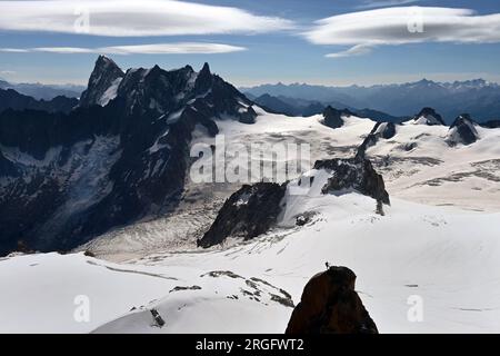 Dôme de Rochefort et Dent du Géant im Massiv Mont Blanc mit Silhouette eines Kletterers auf einem Felsen im Vordergrund Stockfoto