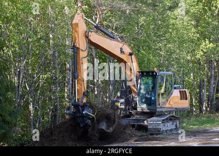 Straßenarbeiten mit Raupenbagger an der Straßenseite, Reparatur des Entwässerungssystems. Stockfoto