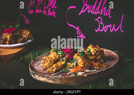 Buddha Schüssel Essen auf einem hölzernen Teller mit rosa Schrift, gezeigt auf einem Food Truck auf einem Festival, schwarzer Hintergrund Stockfoto