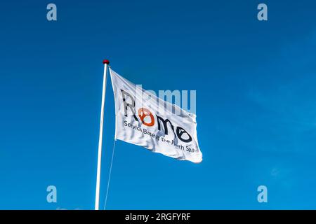 Weiße Flagge mit Inschrift Romo vor blauem Himmel. Romo ist eine dänische Insel im Wattenmeer. Stockfoto