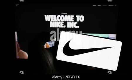 Person, die ein Smartphone mit dem Logo des US-amerikanischen Sportswear-Unternehmens Nike Inc. Auf dem Bildschirm vor der Website hält. Konzentrieren Sie sich auf das Display des Telefons. Stockfoto