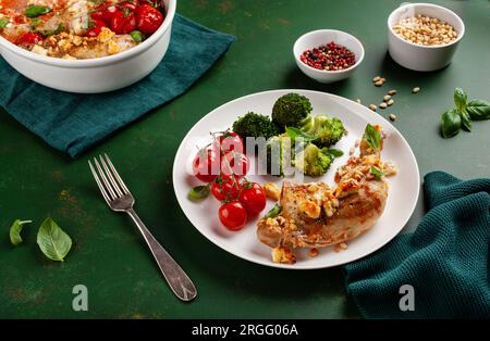 Hühnerschenkel mit Feta-Käse-Tomaten und Brokkoli, gesunde Keto-Mahlzeit Stockfoto