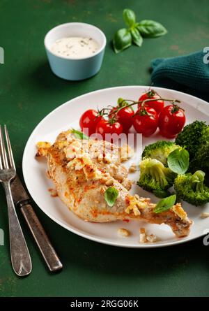 Hühnerschenkel mit Feta-Käse-Tomaten und Brokkoli, gesunde Keto-Mahlzeit Stockfoto