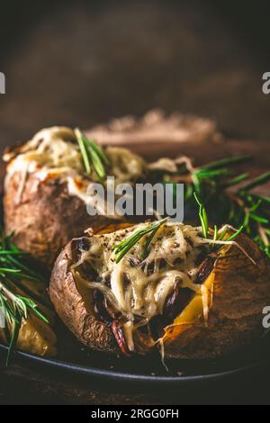 Backkartoffeln mit Pilzen, Sauerrahm und Käse auf rustikalem Holzhintergrund, vertikal mit Kopierbereich Stockfoto