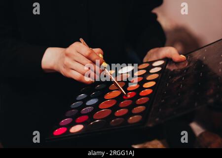 Weibliche Hände mit dekorativer Bürste und Farbpalette für Make-up Stockfoto