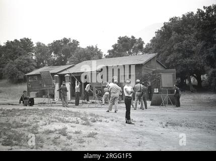 1950er, historisch, ein Hollywood-Film oder Filmset, mit einer speziell konstruierten Landschaft einer kleinen ländlichen Tankstelle. Film- und Beleuchtungstechniker, Kamerafachleute und anderes Filmpersonal stehen am Set in Los Angeles, Kalifornien, USA Stockfoto