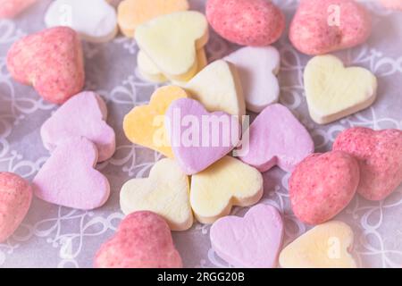 Eine Auswahl an Zucker- und rosafarbenen Schokoladenherzen, Blick von oben, Pastellfarben Stockfoto