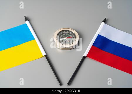 Flaggen der Ukraine und Russlands mit Kompass auf grauem Hintergrund Stockfoto