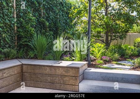 Gemütliche schattige Sitzecke aus Beton und Holz in einem Garten Stockfoto