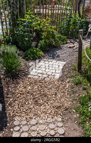Gartenweg aus natürlichen Holzplanken, Steinen, Kies. Gesunder sensorischer Pfad mit verschiedenen Oberflächen. Stockfoto