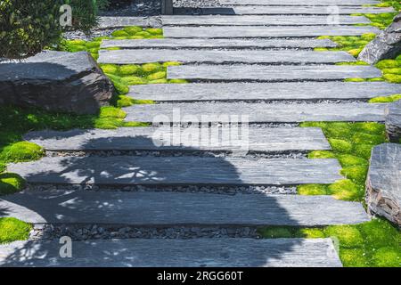 Der Weg mit breiten Steinplatten führt durch einen japanischen Garten Stockfoto