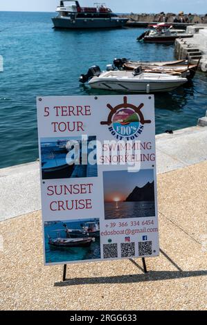 Ein 5 Terre Boat Cruise Tours Schild an der Küste von Monterosso al Mareone, einem von kleinen Fischerdörfern, die von Klippen hängen, viele mit bunten Pastellbäumen Stockfoto