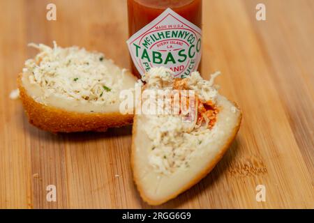 Traditionell gebratener Coxinha auf einem Holztisch im Fokus - brasilianischer Snack. Tabasco-Sauce-Pfeffer Stockfoto