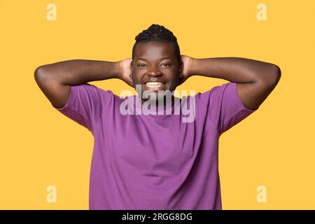 Ein Afrikanischer Mann, Der Hände Hinter Dem Kopf Hält Und Im Studio Steht Stockfoto