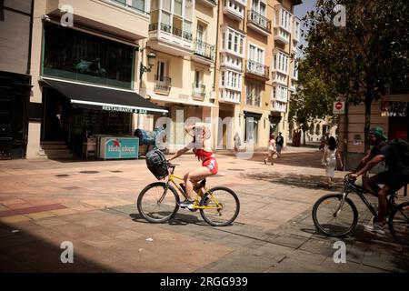 Eine Frau sah, wie sie auf einem Fahrrad winkte, an einem Tag, der von extremen Temperaturen in Vitoria geprägt war. Stockfoto