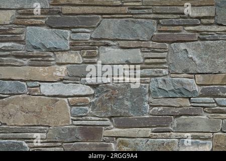 Eine Mauerwand aus Sandstein, die mit einer Ästhetik aus unregelmäßig großen Steinen zusammengesetzt ist, wird aus nächster Nähe gezeigt. Stockfoto