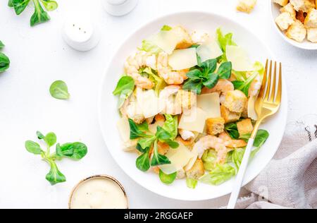 Gourmet-Caesar-Salat mit Garnelen, Eisberg und Salat, Croutons, Parmesan und caesar-Dressing. Weißer Tischhintergrund, Draufsicht Stockfoto