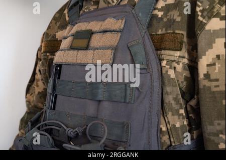 Soldat in grauer kugelsicherer Jacke mit Symbol der ukrainischen Flagge. Stockfoto