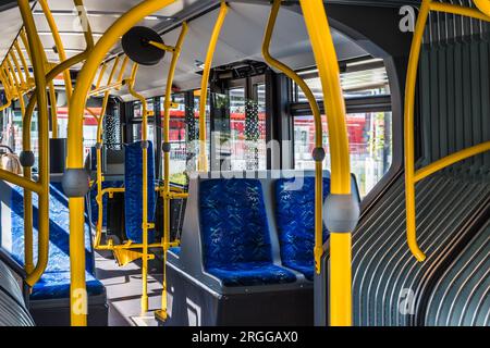 Innendesign eines modernen Busses. Leere Bushaltestelle. Öffentliche Verkehrsmittel in der Stadt. Personenbeförderung. Bus mit blauen Sitzen und gelben Handläufen. Stockfoto