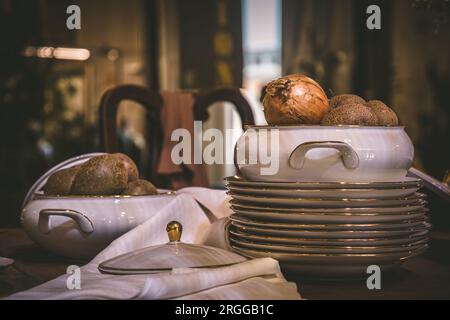 Gestapelte Teller mit goldenem Rand und Schüssel mit Zwiebeln auf einem alten Holztisch Stockfoto