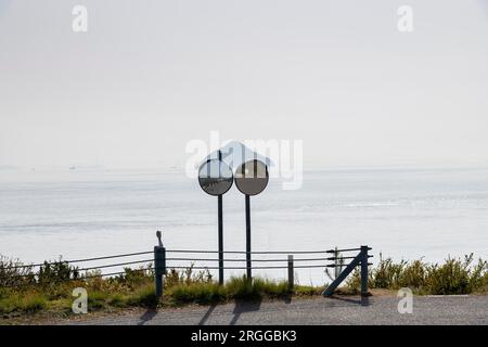 Zwei konvexe Verkehrsspiegel in einer Straßenecke mit Panoramablick auf das japanische Seto-Binnenmeer in der Nähe der Insel Naoshima mit Nebel und Misstrauen Stockfoto