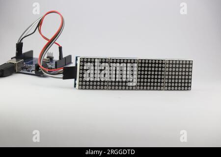 Die LED-Punktmatrixanzeige ist mit einem Mikrocontroller über Überbrückungskabel verbunden, die ein Programm zur Anzeige von Informationen enthalten Stockfoto