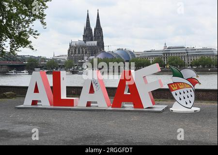 Köln, Deutschland. 09. Aug. 2023. Die 2 m lange Schriftgröße Alaaf steht am Rheinufer vor dem Rhein und dem Kölner Dom als Geschenk des Kölner Karnevalskomitees zum 200. Jahrestag des Karnevals. Alaaf ist weltberühmt als traditionelles Kölner Ausrufezeichen und ein echtes Markenzeichen der rhenischen Lebensfreude. Kredit: Horst Galuschka/dpa/Alamy Live News Stockfoto