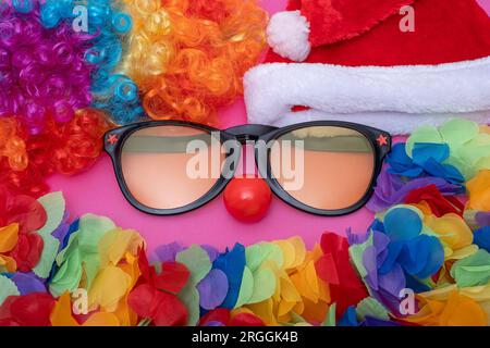 Lustige Party-Set-Sonnenbrille und Weihnachtsmannmütze, Kranz, künstlicher hawaiianischer lei, rote Clownnnase. Cosplay Mit Festlichem Hintergrund Stockfoto