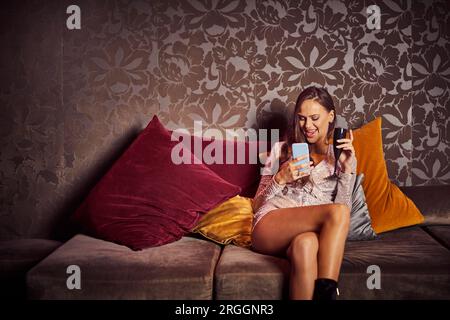 Junge Frau sitzt auf einem Sofa im Nachtclub Stockfoto