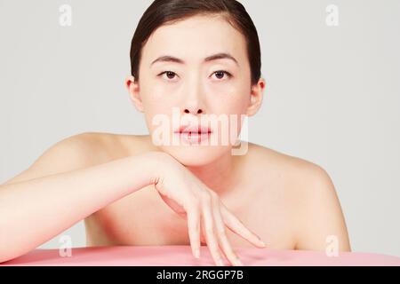 Junge Frau lehnt sich auf Tisch Stockfoto