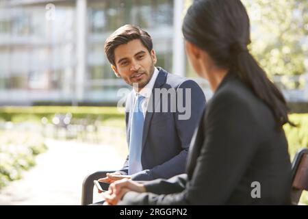 Unternehmer im Gespräch mit seinem Kollegen auf der Parkbank Stockfoto