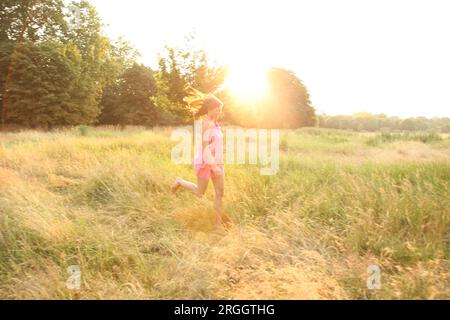 Junge Frau im rosa Kleid im Feld Stockfoto