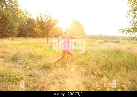 Junge Frau im rosa Kleid im Feld Stockfoto